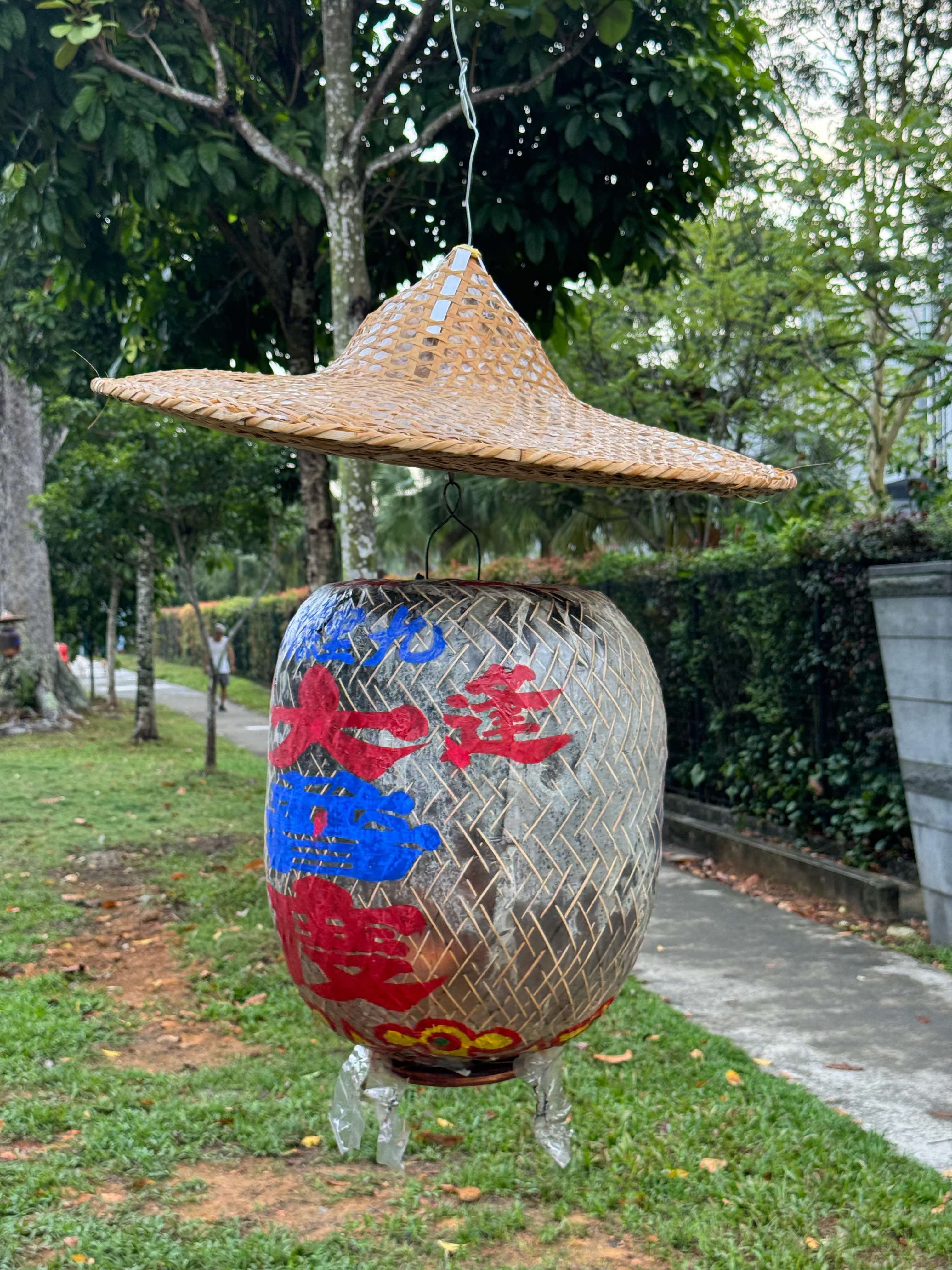 A guiludeng (鬼路灯shaded by a traditional bamboo rain hat. 